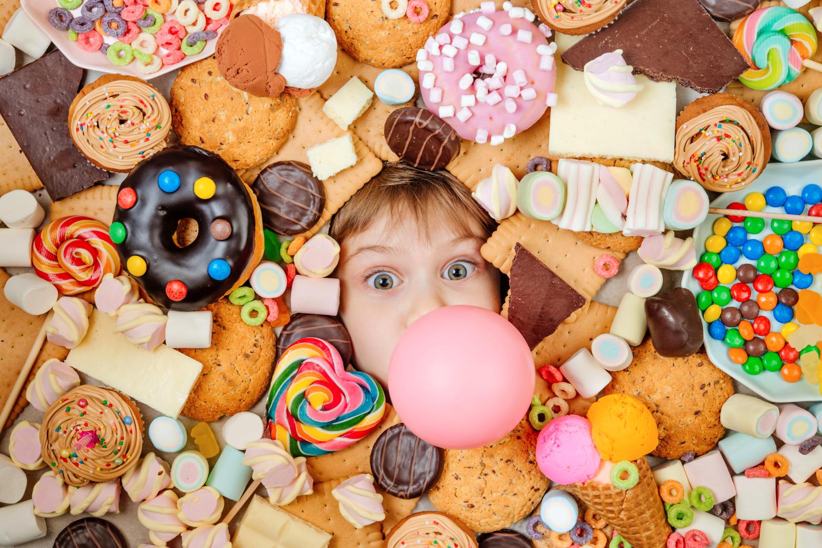 Little girl lying under plenty of sweet foods